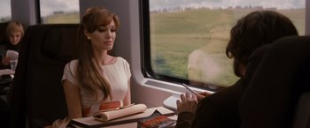 Movie still from “The Tourist” (2010), directed by Florian Henckel von Donnersmarck – A woman sitting in front of a window on a train; Medium shot, Over the shoulder angle