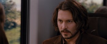 Movie still from “The Tourist” (2010), directed by Florian Henckel von Donnersmarck – A man with long brown hair and a beard stares at the camera; Close Up shot, Over the shoulder angle