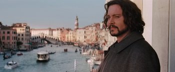 Movie still from “The Tourist” (2010), directed by Florian Henckel von Donnersmarck – A man standing in front of a body of water; Close Up shot, Over the shoulder angle