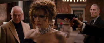 Movie still from “The Tourist” (2010), directed by Florian Henckel von Donnersmarck – A woman in a black dress holding a gun in her hand; Close Up shot, Over the shoulder angle