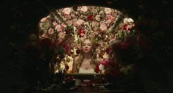 A woman sitting in front of a bunch of flowers