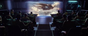 Movie still from “Ender's Game” (2013), directed by Gavin Hood – A group of people sitting in front of a large screen; Extreme Wide shot, Over the shoulder angle