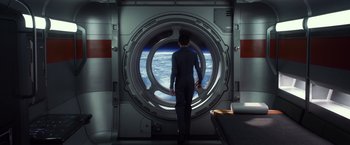 Movie still from “Ender's Game” (2013), directed by Gavin Hood – A man standing in front of an open window looking out at the earth; Wide shot, Overhead angle