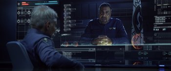 Movie still from “Ender's Game” (2013), directed by Gavin Hood – A man sitting in front of a television screen; Medium shot, Over the shoulder angle