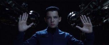 Movie still from “Ender's Game” (2013), directed by Gavin Hood – A young boy in a blue jacket is holding a pair of helmets in front of him; Close Up shot, Low angle