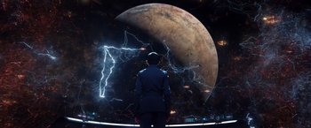 Movie still from “Ender's Game” (2013), directed by Gavin Hood – A man standing in front of an image of the moon; Extreme Wide shot, High angle