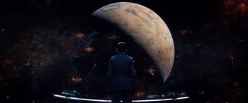 Movie still from “Ender's Game” (2013), directed by Gavin Hood – A man standing in front of an image of a planet; Wide shot, High angle