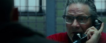 Movie still from “The Town” (2010), directed by Ben Affleck – An older man wearing glasses is talking on a cell phone; Close Up shot, Over the shoulder angle