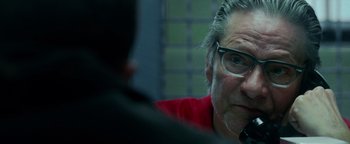 Movie still from “The Town” (2010), directed by Ben Affleck – An older man wearing glasses and a red t - shirt; Close Up shot, Over the shoulder angle