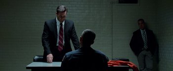 Movie still from “The Town” (2010), directed by Ben Affleck – A man in a suit and tie standing in front of another man; Medium shot, Over the shoulder angle