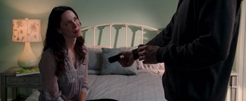 Movie still from “The Town” (2010), directed by Ben Affleck – A woman sitting on a bed while a man holds a remote; Medium shot, Over the shoulder angle