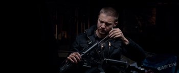 Movie still from “The Town” (2010), directed by Ben Affleck – A man in black jacket holding a rifle; Medium shot, Over the shoulder angle