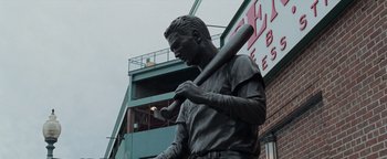 Movie still from “The Town” (2010), directed by Ben Affleck – A statue of a baseball player holding a baseball bat; Wide shot, Low angle