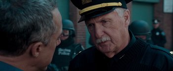 Movie still from “The Town” (2010), directed by Ben Affleck – A man in a police uniform talking to another man; Close Up shot, Over the shoulder angle