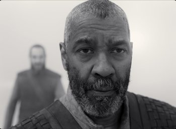 Movie still from “The Tragedy of Macbeth” (2021), directed by Joel Coen – A black and white photo of a man with a beard; Close Up shot, Over the shoulder angle
