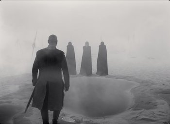 Movie still from “The Tragedy of Macbeth” (2021), directed by Joel Coen – A man standing in front of a group of people in the fog; Wide shot, Over the shoulder angle