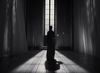Movie still from “The Tragedy of Macbeth” (2021), directed by Joel Coen – A person standing in front of a window in a room; Wide shot, Low angle