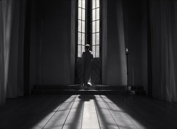 Movie still from “The Tragedy of Macbeth” (2021), directed by Joel Coen – A man sitting in front of a window in a room; Wide shot, Low angle