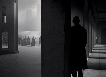 Movie still from “The Tragedy of Macbeth” (2021), directed by Joel Coen – A man standing in front of a group of people; Wide shot, Over the shoulder angle