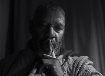 Movie still from “The Tragedy of Macbeth” (2021), directed by Joel Coen – A black and white photo of a man holding a cigarette; Extreme Close Up shot, Low angle