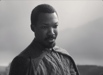 Movie still from “The Tragedy of Macbeth” (2021), directed by Joel Coen – A black and white photo of a man with a beard; Close Up shot, High angle