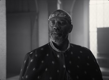 Movie still from “The Tragedy of Macbeth” (2021), directed by Joel Coen – An older man wearing a crown and a robe; Medium shot, Low angle