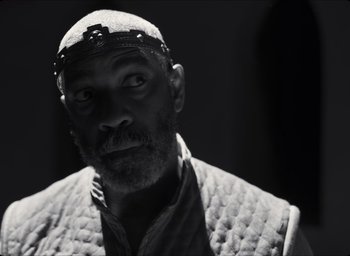 Movie still from “The Tragedy of Macbeth” (2021), directed by Joel Coen – A black and white photo of a man wearing a turban; Close Up shot, Low angle