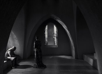 Movie still from “The Tragedy of Macbeth” (2021), directed by Joel Coen – A woman standing in front of a window in a room; Wide shot, Low angle