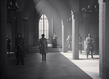 Movie still from “The Tragedy of Macbeth” (2021), directed by Joel Coen – A group of people standing in front of a window in a building; Wide shot, High angle