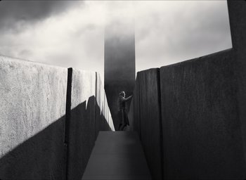 Movie still from “The Tragedy of Macbeth” (2021), directed by Joel Coen – A person walking down a ramp in a cloudy sky; Extreme Wide shot, Low angle
