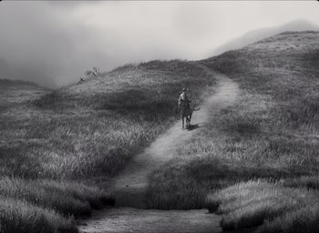 Movie still from “The Tragedy of Macbeth” (2021), directed by Joel Coen – A person on a horse walking down a trail; Extreme Wide shot, High angle