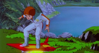 Movie still from “The Transformers: The Movie” (1986), directed by Nelson Shin – A boy is standing on a hill near a body of water; Wide shot, Low angle