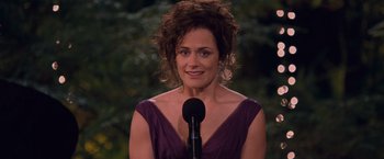 Movie still from “The Twilight Saga: Breaking Dawn - Part 1” (2011), directed by Bill Condon – A woman in a purple dress standing at a microphone; Medium shot, Over the shoulder angle