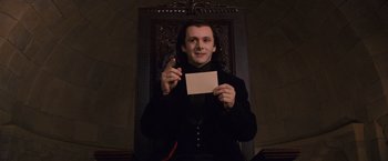 Movie still from “The Twilight Saga: Breaking Dawn - Part 1” (2011), directed by Bill Condon – A man holding a piece of paper in front of a chair; Medium shot, Low angle