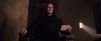 Movie still from “The Twilight Saga: Breaking Dawn - Part 1” (2011), directed by Bill Condon – A man sitting in a chair holding an open envelope; Medium shot, Low angle