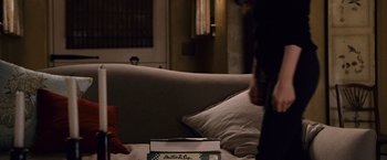 Movie still from “The Twilight Saga: Breaking Dawn - Part 2” (2012), directed by Bill Condon – A box sitting on top of a couch next to pillows; Medium shot, Over the shoulder angle