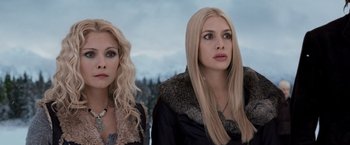 Two blonde women standing next to each other in a snowy field