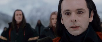 Movie still from “The Twilight Saga: Breaking Dawn - Part 2” (2012), directed by Bill Condon – A man's face with two women in the background; Close Up shot, Over the shoulder angle