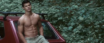 Movie still from “The Twilight Saga: Eclipse” (2010), directed by David Slade – A shirtless man standing next to a red car; Medium shot, High angle