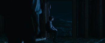Movie still from “The Twilight Saga: Eclipse” (2010), directed by David Slade – A man sitting on a chair in a dark room; Wide shot, Over the shoulder angle