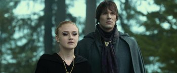 Movie still from “The Twilight Saga: Eclipse” (2010), directed by David Slade – A young man and a young woman standing next to each other in front of trees; Medium shot, Low angle