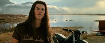 Movie still from “The Twilight Saga: New Moon” (2009), directed by Chris Weitz – A person standing next to a motorcycle near a body of water; Close Up shot, Over the shoulder angle