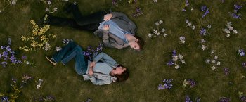 Movie still from “The Twilight Saga: New Moon” (2009), directed by Chris Weitz – Two people laying in the grass next to purple flowers; Wide shot, Overhead angle