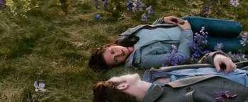 Movie still from “The Twilight Saga: New Moon” (2009), directed by Chris Weitz – Two people laying in the grass next to flowers; Medium shot, High angle