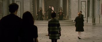 Movie still from “The Twilight Saga: New Moon” (2009), directed by Chris Weitz – A woman standing in front of a group of people in a room; Wide shot, Over the shoulder angle