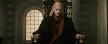 Movie still from “The Twilight Saga: New Moon” (2009), directed by Chris Weitz – A man sitting in a chair wearing a black coat and a red scarf; Medium shot, Low angle