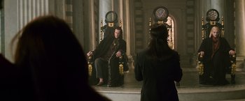 Movie still from “The Twilight Saga: New Moon” (2009), directed by Chris Weitz – A man sitting on a throne in a room with a woman taking a picture of him; Wide shot, Over the shoulder angle