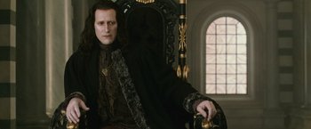 Movie still from “The Twilight Saga: New Moon” (2009), directed by Chris Weitz – A man sitting in a chair wearing a black robe; Medium shot, Low angle
