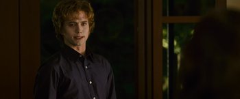 Movie still from “The Twilight Saga: New Moon” (2009), directed by Chris Weitz – A young man standing in front of a window in a dark room; Medium shot, Over the shoulder angle
