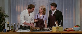 Movie still from “The Ugly Truth” (2009), directed by Robert Luketic – Three people standing in front of a stove with food on it; Medium shot, Over the shoulder angle